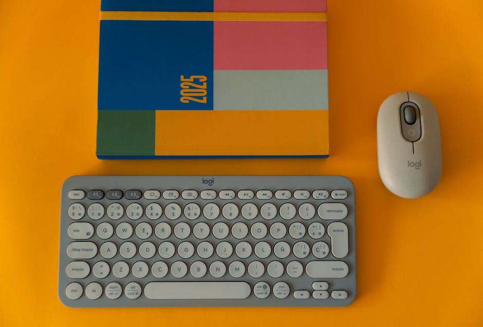 Flat lay of a colorful 2025 planner with keyboard and mouse on a bright orange background
