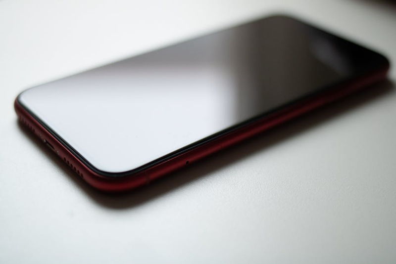 Close-up image of a red smartphone lying on a white surface with a modern sleek design